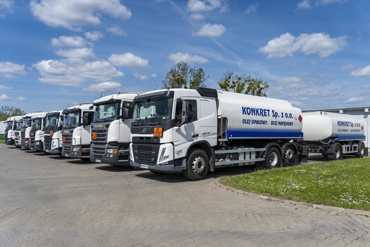 Biała autocysterna KONKRET Sp. z o.o. z naczepą, zaparkowana w rzędzie pojazdów firmy, przeznaczona do transportu oleju opałowego i oleju napędowego w Radomiu